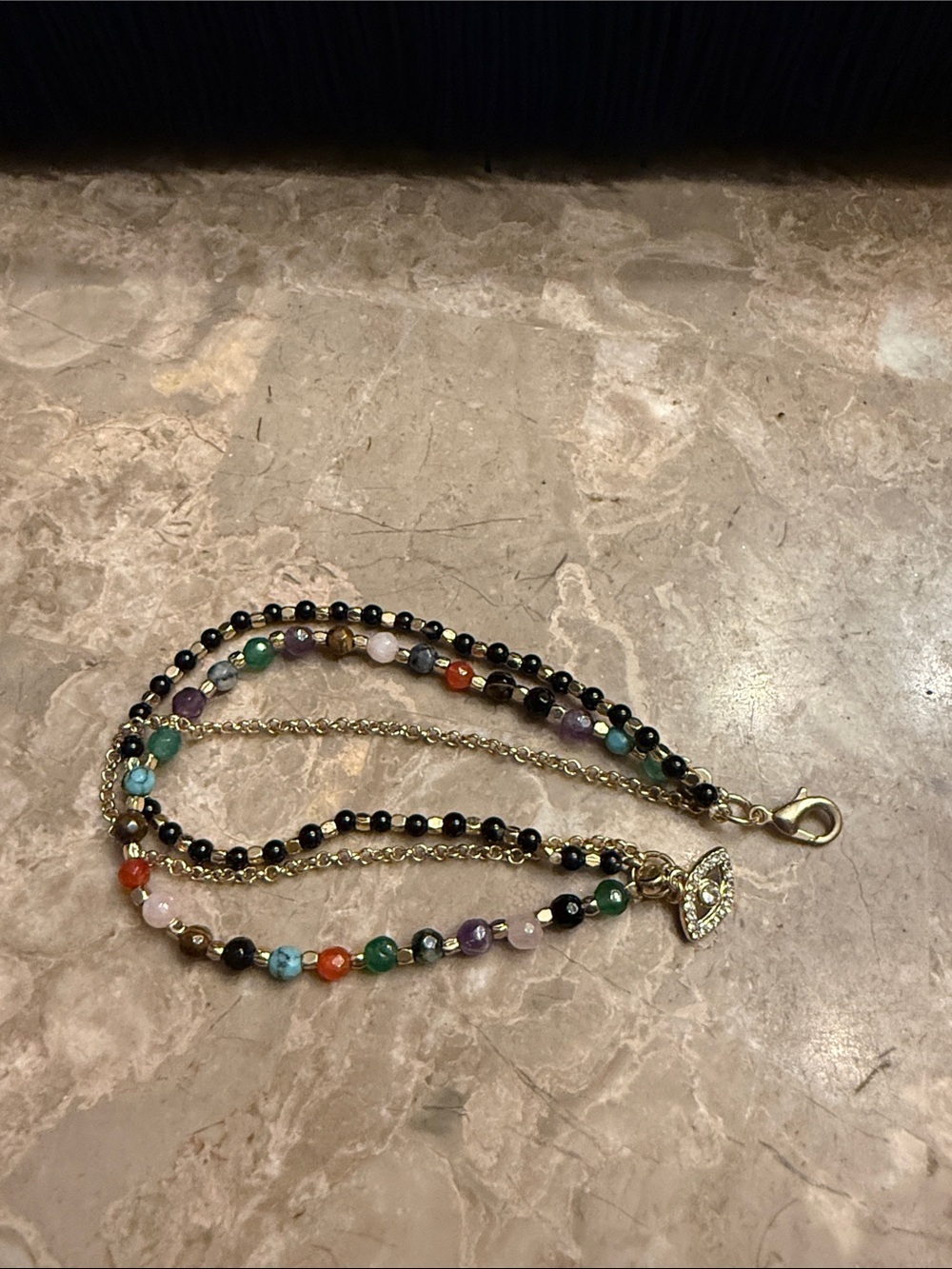Gold tone, three strand chain and beaded bracelet with rhinestone evil eye charm